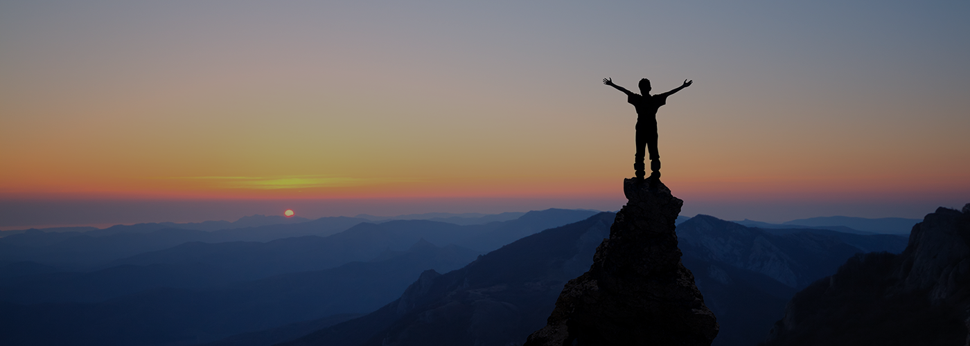 person standing on top of mountain with arms outstretched