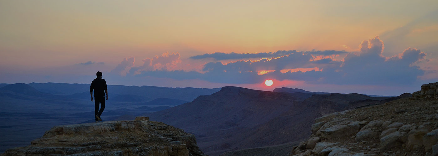 man standing on top of a mountain at sunset